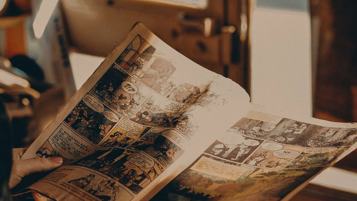 A person leafing through an old comic by a window