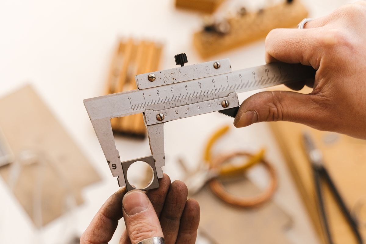 Measuring an item with a caliper at a workbench